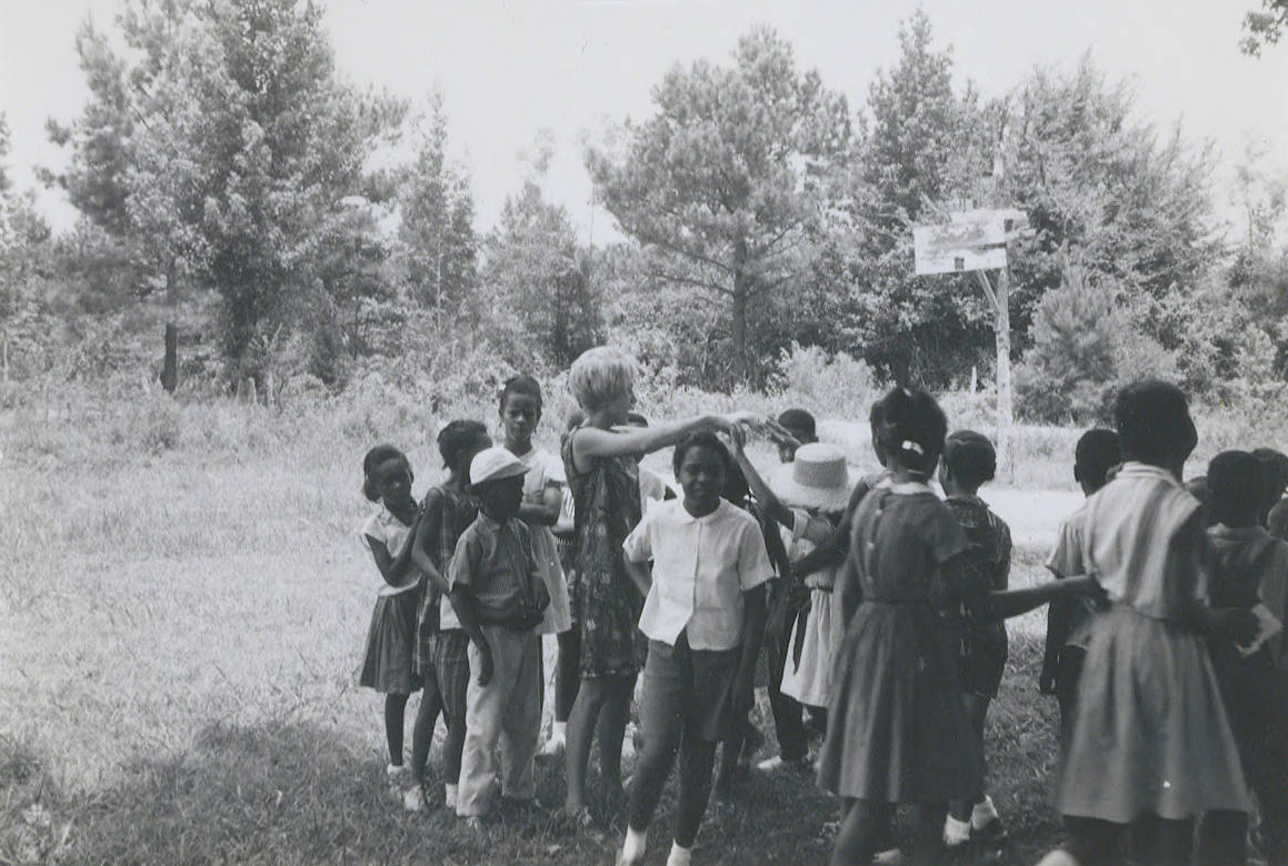 Carole Gross Colca in a field with children in Mississippi